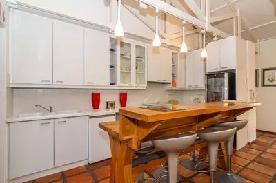 a kitchen with white cabinets and a wooden table at Fynbos House in Hermanus