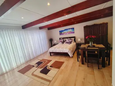 a bedroom with a bed and a table and a desk at Villa Rosa Luxury in Cape Town
