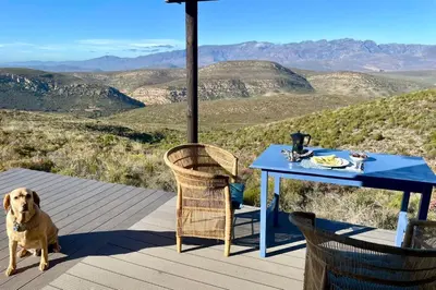 a dog sitting next to a table on a deck at Skuilkrans Private Nature Reserve in McGregor