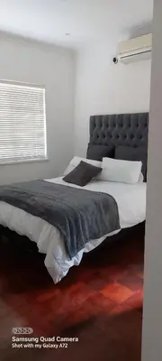 a bedroom with a large bed with a black headboard at COMFORT LODGE milnerton, Cape Town in Cape Town