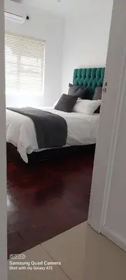 a bedroom with a large bed with a green headboard at COMFORT LODGE milnerton, Cape Town in Cape Town