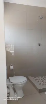a white bathroom with a toilet and a shower at COMFORT LODGE milnerton, Cape Town in Cape Town