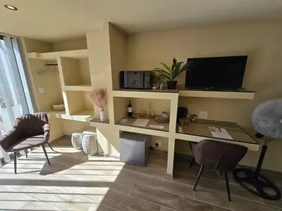 a living room with a desk with a tv and chairs at Die Regte Rede in Cape Town