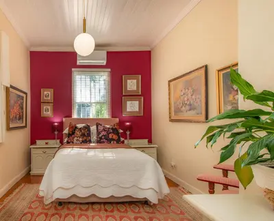 a bedroom with a bed and a red wall at Beautiful country house set in lush garden in Wellington