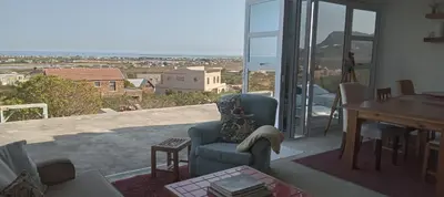 a living room with a chair and a table on a balcony at Red Disa in Malkopvlei