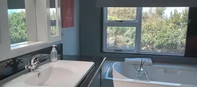 a bathroom with two sinks and two windows at Red Disa in Malkopvlei