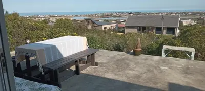 a bench sitting on a balcony with a view of the ocean at Red Disa in Malkopvlei
