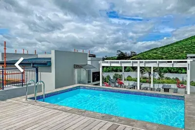 a swimming pool in front of a house at Luxury at The Den in Stellenbosch