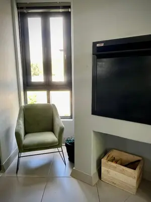 a living room with a chair and a large television at Luxury at The Den in Stellenbosch