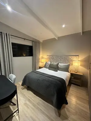a bedroom with a large bed with two lamps and a desk at Somerset-West PRIME SPOT- Solar Powered! in Cape Town