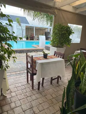 a patio with a table and chairs and a pool at Delash Pine Villa in Cape Town