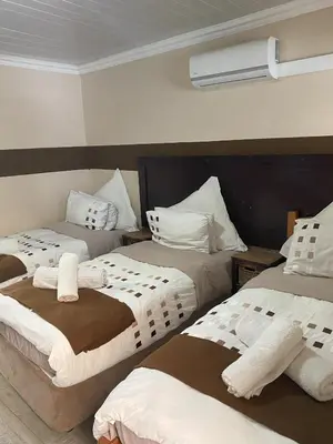 a hotel room with two beds with towels on them at Delash Pine Villa in Cape Town