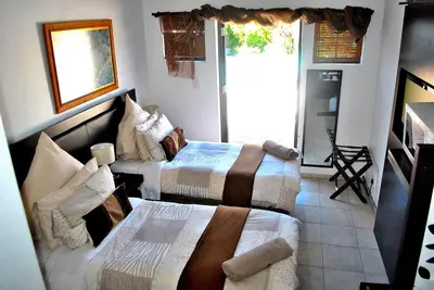 a room with two beds in a room with a window at Delash Pine Villa in Cape Town