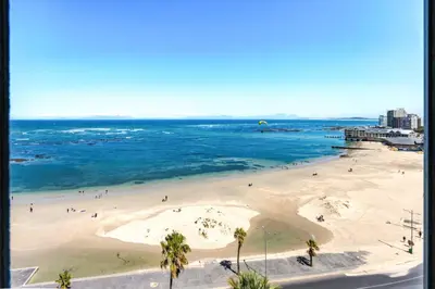 a beach with palm trees and people in the water at Elana Beachfront Condo in Strand