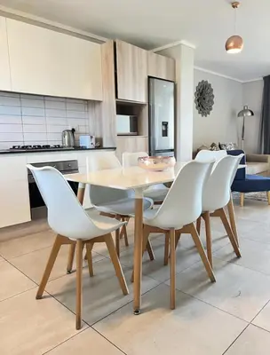 a kitchen with a wooden table and white chairs at Stylish waters edge apartment in Cape Town