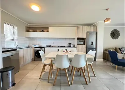 a kitchen with a table and chairs in a room at Stylish waters edge apartment in Cape Town