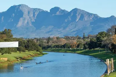 people in boats on a river with mountains in the background at Royal Boland in Paarl