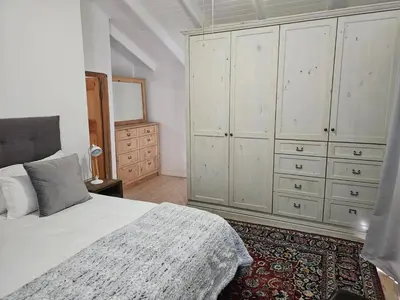 a bedroom with a white bed and a dresser at PinotageLuxuryCollection 9A Herte Suite in Stellenbosch