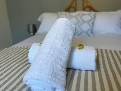 a bed with towels on top of it at Mountain Views, beach walks, heart of old village in Gordonʼs Bay