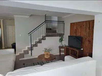 a living room with a white couch and a staircase at Holihome in Brackenfell