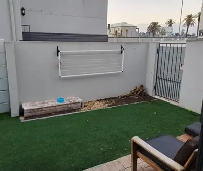 a patio with green grass on a white building at Holihome in Brackenfell