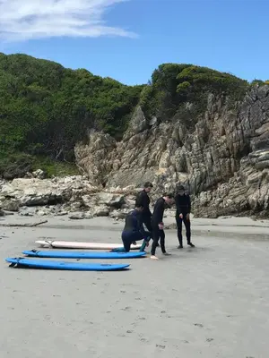 a group of people standing around surfboards on a beach at Awesome room in surf house in Hermanus