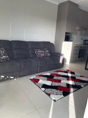 a living room with a black couch and a rug at Rozama's little nest in Cape Town