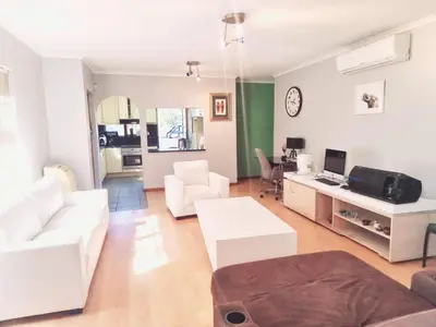 a living room with white furniture and a desk at 3 bedroom garden house in Tableview in Table View