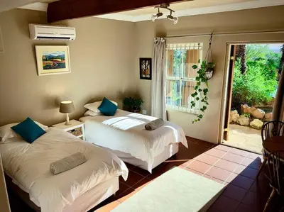 a bedroom with two beds and a window at Tuscan Farmhouse near Franschhoek in Simondium