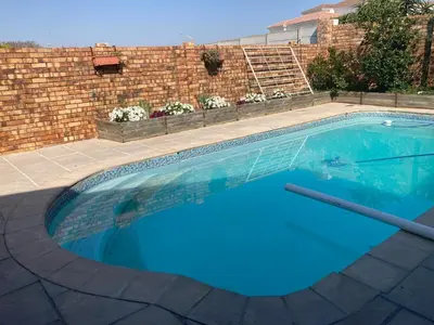 a swimming pool with blue water in front of a brick wall at Budget Boutique in Blomtuin