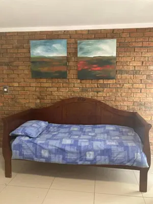 a bed in a room with three paintings on a brick wall at Budget Boutique in Blomtuin