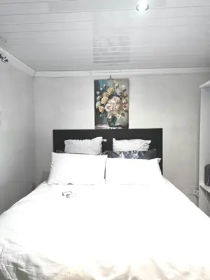 a bedroom with a white bed with a painting on the wall at Aqua Breeze in Cape Town