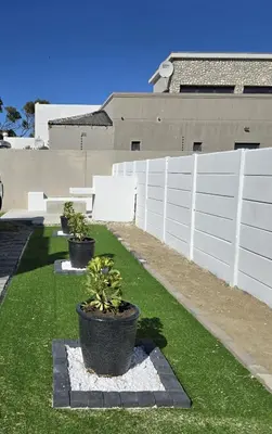 a white fence with two potted plants on the grass at Aqua Breeze in Cape Town