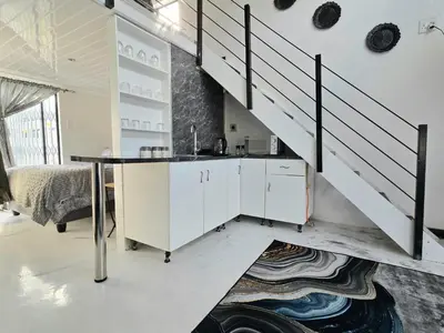 a kitchen with white cabinets and a staircase at Aqua Breeze in Cape Town