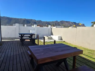 a wooden deck with two picnic tables on a roof at Aqua Breeze in Cape Town