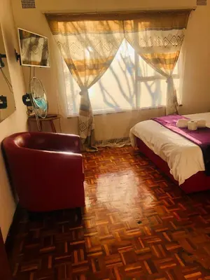 a bedroom with a bed and a chair and a window at ggu in Cape Town