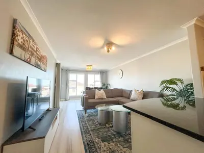a living room with a couch and a tv at Century Hideaway with Mountain views, Security, FREE Parking in Cape Town