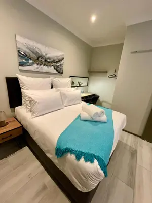 a bedroom with a large bed with a blue blanket on it at Tehillah on Boom in Bothasig