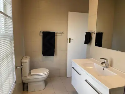a white bathroom with a toilet and a sink at The Nook in Stellenbosch