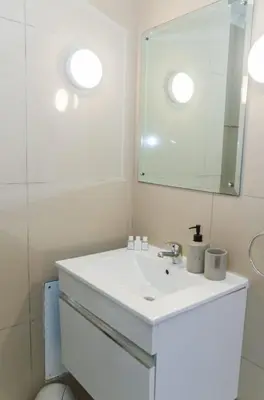 a white bathroom with a sink and a mirror at Sunset Accommodation in Strand in Strand