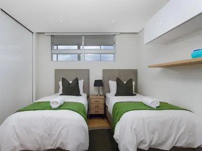 two beds with green and white sheets in a room at Sunsets on Beach Strand in Cape Town