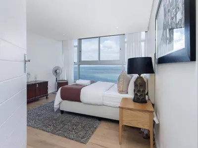 a bedroom with a bed with a view of the ocean at Sunsets on Beach Strand in Cape Town