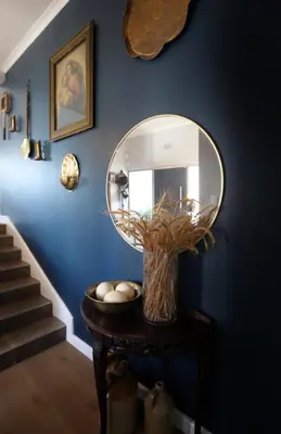 a hallway with a round mirror on a blue wall at De Boerderij in Strand