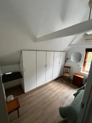 a bedroom with white cabinets and a bed and a window at Koetshuis on High Street in Paarl