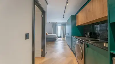 a kitchen with green cabinets and a room with a bed at Little island in Cape Town