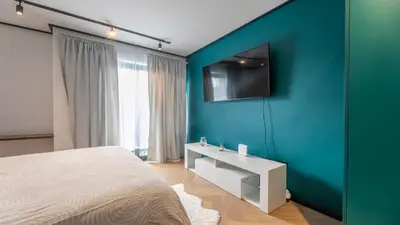 a bedroom with a blue wall with a bed and a tv at Little island in Cape Town