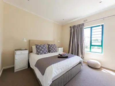 a bedroom with a bed with blue pillows and a window at Paradyskloof home in Stellenbosch