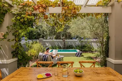 a garden with a woman sitting on a couch under a pergola at Duplicate in Franschhoek
