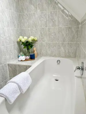 a white bath tub in a bathroom with flowers at Duplicate in Franschhoek