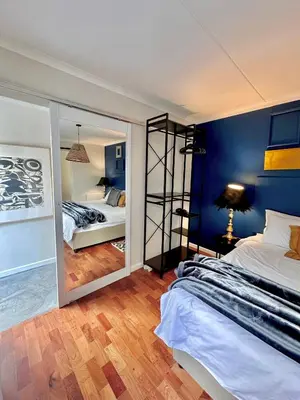 a bedroom with blue walls and a large mirror at Die Klein Huis in Cape Town